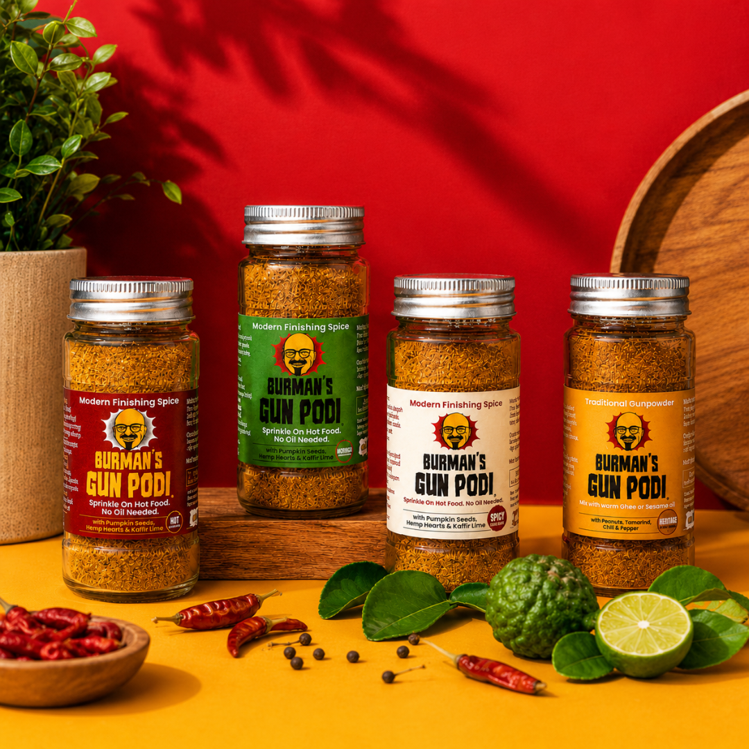 Jars of 'Burmans Gun Podi' spice on a wooden surface with red and yellow background