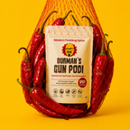 Burman's Gun Podi spice pouch displayed with red chilies in a mesh bag on a yellow background - a vegan, gluten-free finishing spice with pumpkin seeds, hemp hearts, and kaffir lime